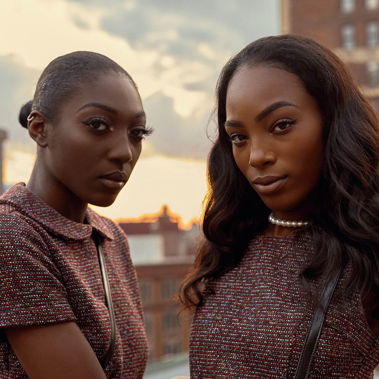 After: Two women in patterned tops on a rooftop at sunset