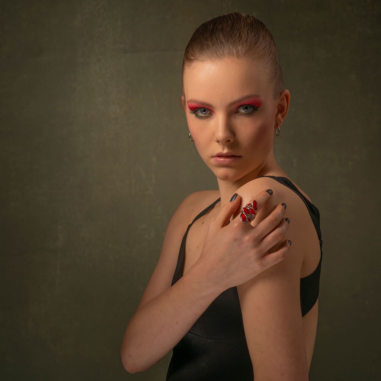 Before: Portrait of a woman with red eye makeup and a hand on her shoulder