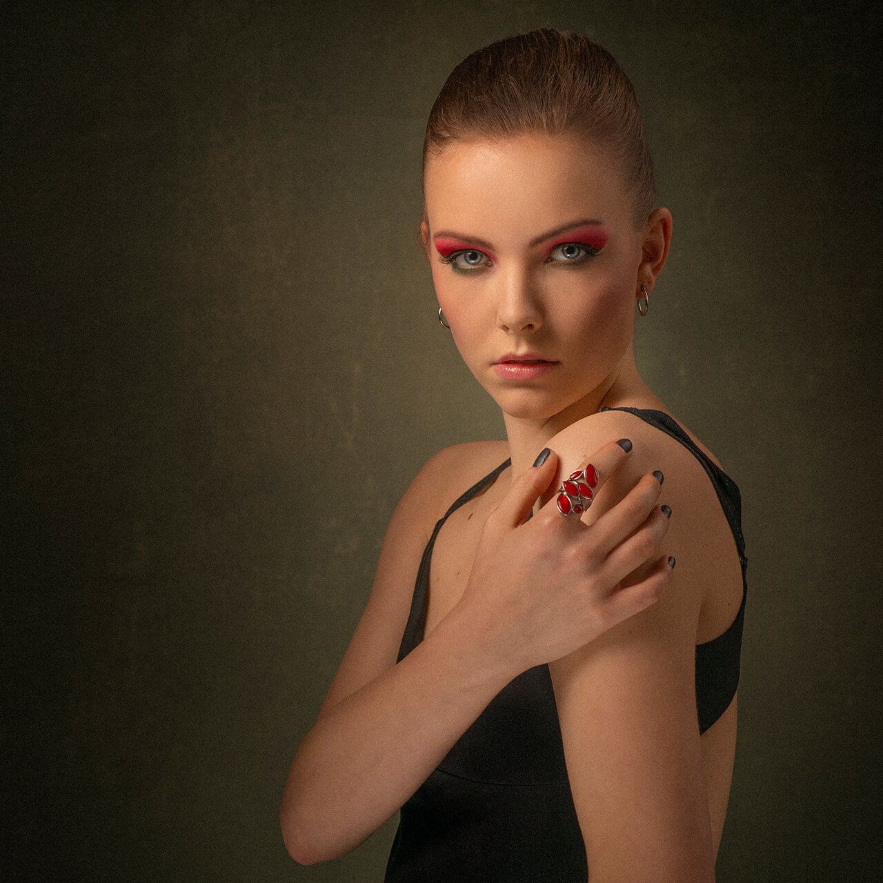 After: Portrait of a woman with red eye makeup and a hand on her shoulder